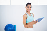 Cute slender woman working on her tablet standing in fitness hall