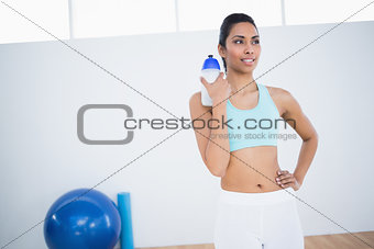 Calm sporty woman posing holding sports bottle