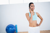 Content smiling woman in sportswear phoning with smartphone