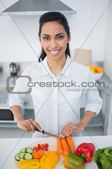 Lovely smiling woman cutting vegetables smiling at camera