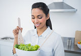 Cute calm woman preparing salad standing in kitchen