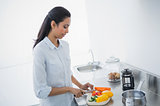 Pretty black haired woman preparing meal in bright kitchen