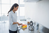 Content woman preparing salad standing in bright kitchen