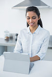Cute woman using her tablet standing in bright kitchen