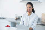 Beautiful woman working on her tablet standing in her kitchen