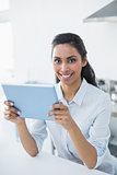 Attractive peaceful woman holding her tablet smiling cheerfully at camera