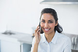 Content smiling woman phoning with her smartphone in bright kitchen