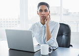 Attractive thoughtful businesswoman sitting at her desk