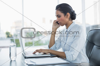 Calm concentrated businesswoman sitting at her desk working