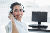 Smiling female agent wearing a headset sitting in bright office