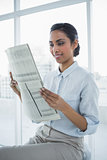 Lovely smiling calm businesswoman reading newspaper