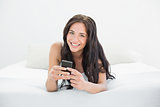 Beautiful woman with mobile phone in bed