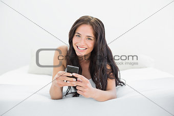 Beautiful woman with mobile phone in bed