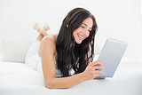 Smiling woman using tablet PC in bed