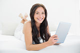 Portrait of a smiling woman with tablet PC in bed