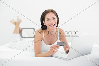 Portrait of a casual woman doing online shopping in bed