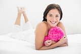 Smiling woman lying in bed with heart shaped pillow