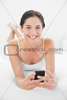 Portrait of a smiling woman with mobile phone in bed