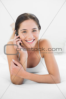 Portrait of a smiling woman using mobile phone in bed