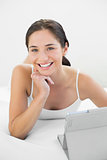 Portrait of a smiling casual woman with tablet PC in bed