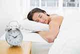 Sleeping woman with blurred alarm clock on bedside table