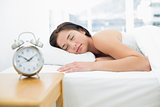 Sleeping woman with blurred alarm clock in foreground