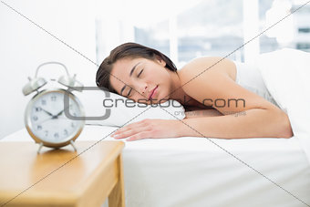 Sleeping woman with blurred alarm clock in foreground