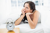 Woman in bed with alarm clock in foreground