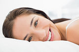 Pretty smiling young woman resting in bed