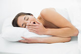 Young woman yawning in bed