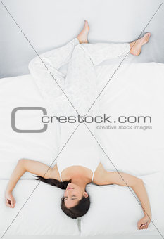 Full length of a woman sleeping in bed with eyes closed