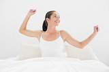 Smiling woman stretching arms in bed