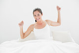Smiling woman stretching her arms in bed