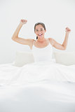 Cheerful woman stretching her arms in bed