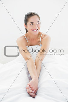 Smiling woman looks away in bed