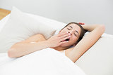 Woman yawning in bed with eyes closed