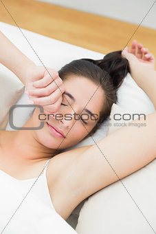 Beautiful woman stretching arms in bed