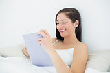 Smiling woman reading a book in bed