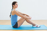 Profile shot of a fit woman sitting upright on exercise mat