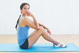 Fit woman sitting upright on exercise mat