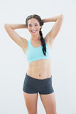 Fit smiling woman standing with hands behind head