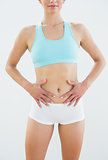 Mid section of a fit woman in sportswear with hands on belly