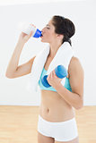 Fit woman with dumbbell drinking water
