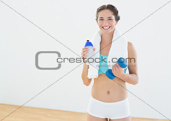 Woman with dumbbells and water bottle at fitness studio