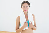 Fit woman with towel around neck at fitness studio