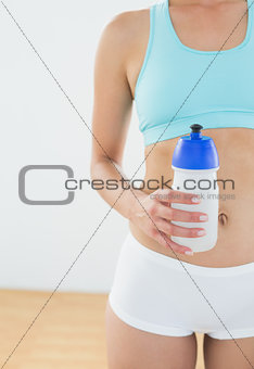 Fit woman holding water bottle at fitness studio