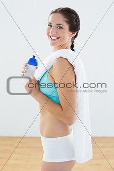 Fit woman with water bottle and towel at fitness studio