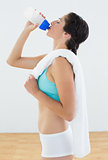 Fit young woman drinking water at fitness studio