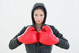 Serious young woman in red boxing gloves and black hood