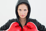 Serious woman in red boxing gloves and black hood